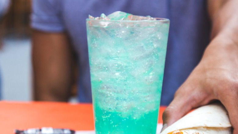A customer grabs a burrito next to an icy Baja Blast
