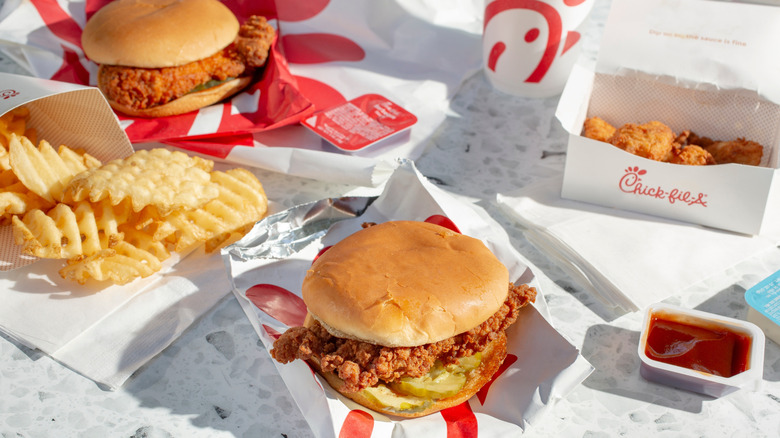 An assortment of Chick-fil-A products, including chicken sandwiches, waffle fries, nuggets, and sauce