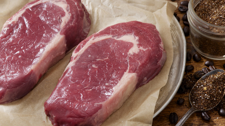 Raw steaks on parchment paper with spice rub