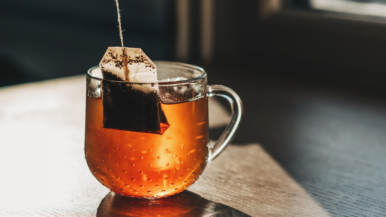 Tea bag in a clear mug with tea.