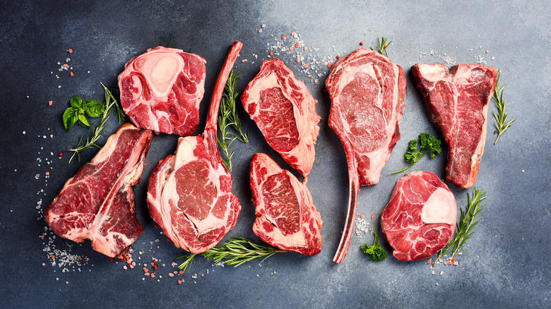 Different types of stake on a black table with salt and herbs