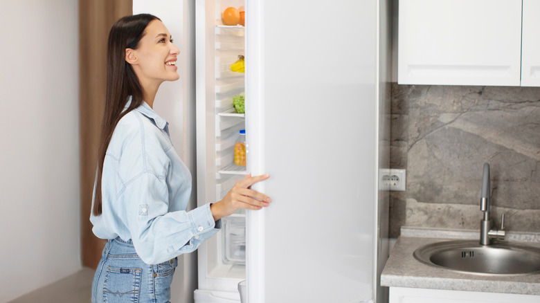 A person opening a fridge and looking into the door